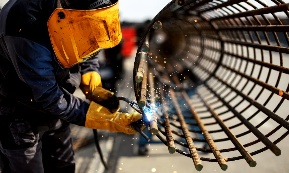 Welder in a protective mask working on steel reinforcement, sparks flying
