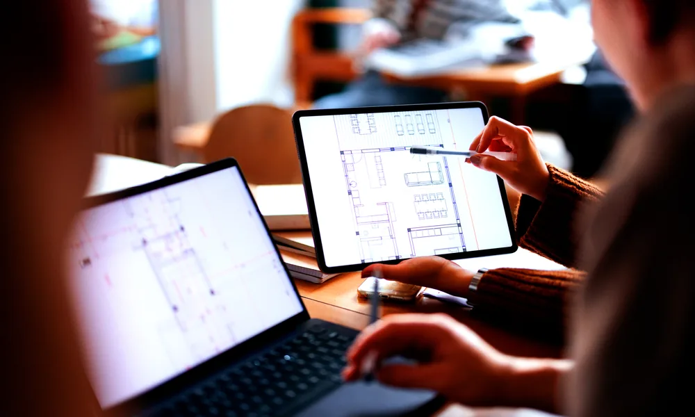 Project managers reviewing floor plans on a tablet and laptop